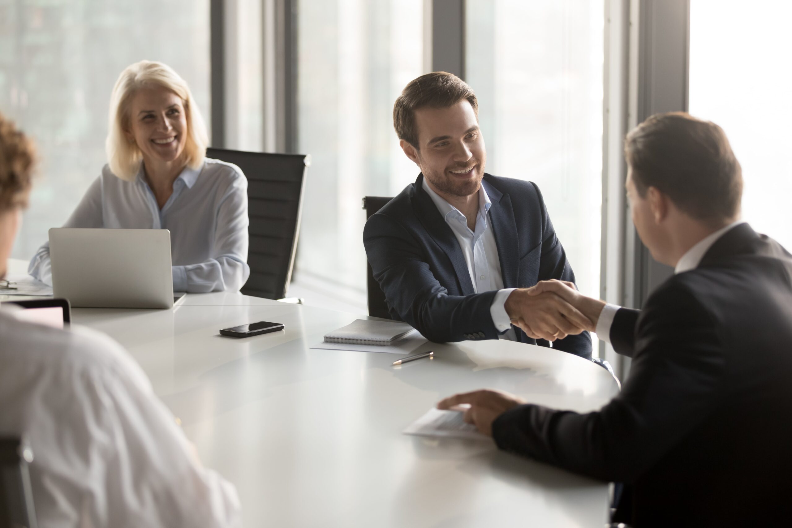 Business professionals shaking hands in a meeting, symbolizing agreement and collaboration.