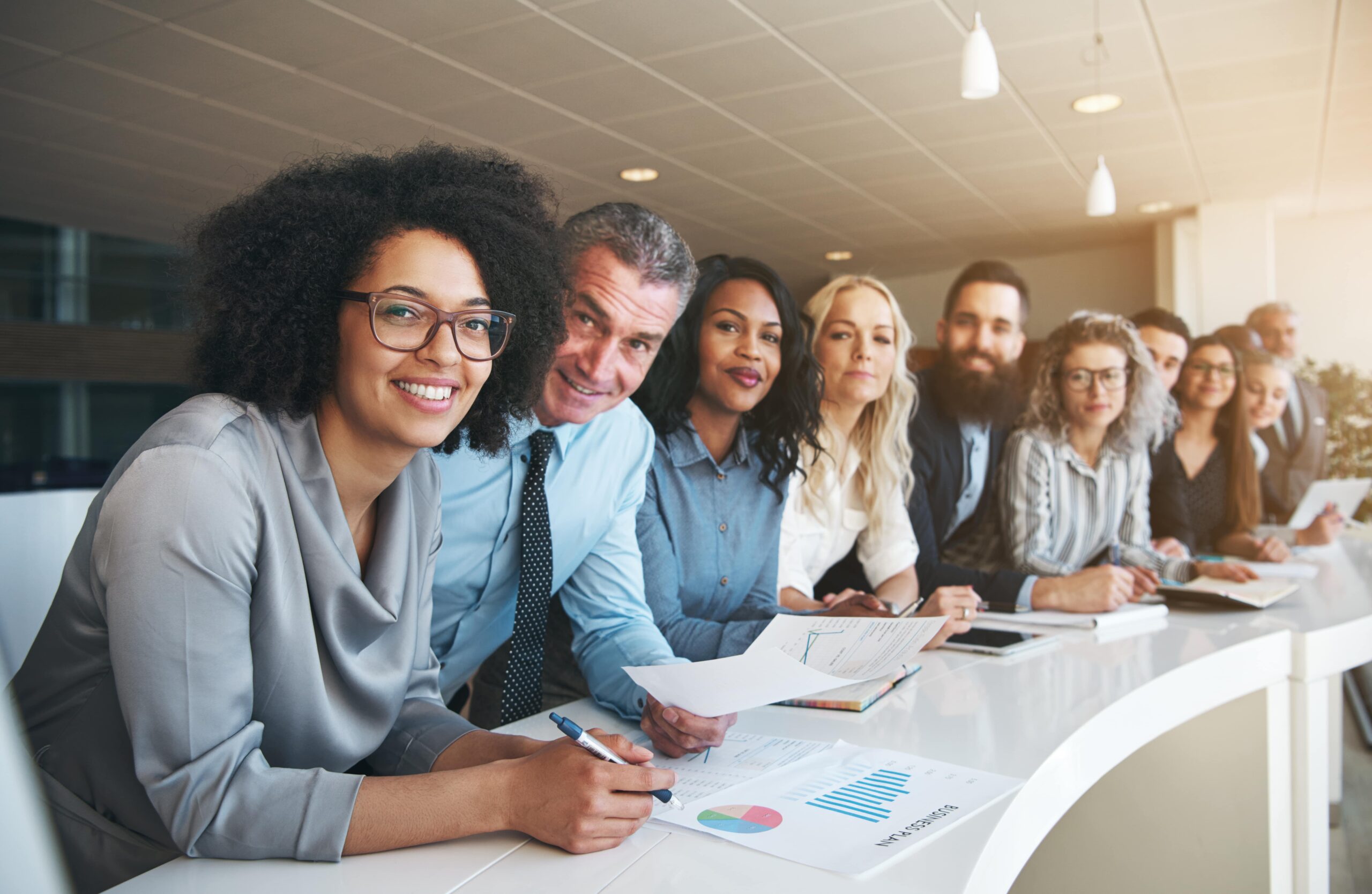 Diverse business team smiling during a meeting, reviewing documents and charts together